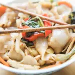 Bowl of drunken noodles with chopsticks resting on top