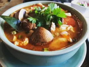 Bowl of spicy tom yum soup with mushrooms and cilantro from Lemongrass Thai Cuisine