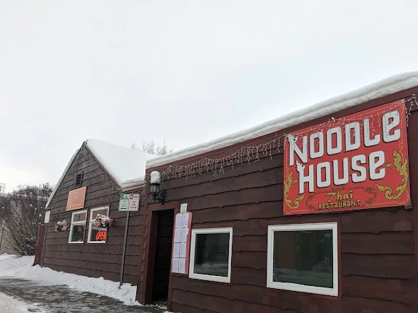 Noodle House Thai Restaurant storefront with its red sign in winter snow, Fairbanks