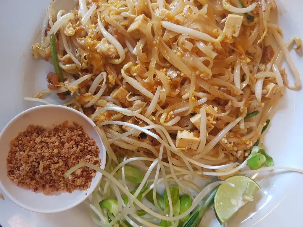 Plate of pad thai with crushed peanuts, bean sprouts and lime on the side