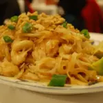 Mound of pad thai noodles with green onion and a wedge of lime