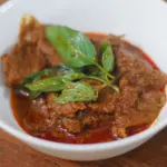 Thick panang curry with meat and Thai basil in a white bowl