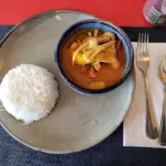 Bowl of red curry with chicken and bamboo shoots, served with jasmine rice