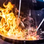 Flames leaping from a wok during stir-frying
